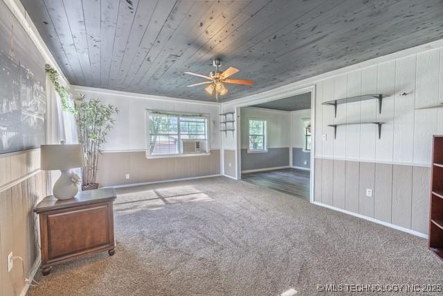 604 N N W, Konawa, OK 74849 - unfurnished living room with crown molding, wood ceiling, carpet flooring, a ceiling fan, and a wainscoted wall