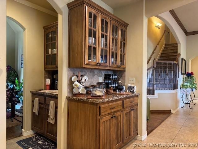 2511 E 138th St S, Bixby, OK 74008 - bar featuring ornamental molding, arched walkways, tasteful backsplash, light tile patterned flooring, and stairway