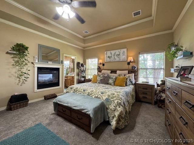2511 E 138th St S, Bixby, OK 74008 - bedroom featuring a raised ceiling, multiple windows, dark carpet, crown molding, and a glass covered fireplace