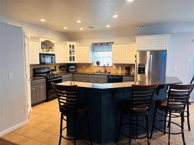 10219 N 119th E Ave, Owasso, OK 74055 - kitchen featuring black appliances, tasteful backsplash, dark countertops, a kitchen breakfast bar, and a kitchen island