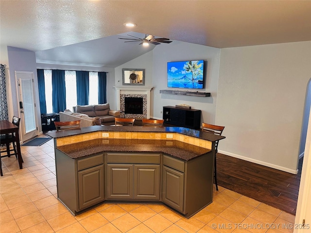 10219 N 119th E Ave, Owasso, OK 74055 - kitchen with a ceiling fan, a fireplace, lofted ceiling, a kitchen island, and open floor plan