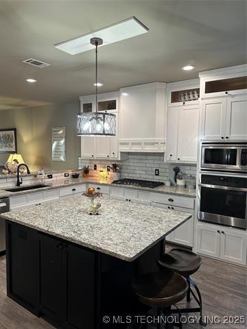 1821 W Lincoln St N, Broken Arrow, OK 74012 - kitchen featuring stainless steel appliances, a kitchen island, dark wood finished floors, white cabinetry, and recessed lighting