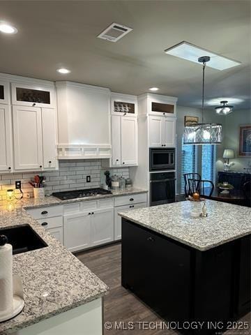 1821 W Lincoln St N, Broken Arrow, OK 74012 - kitchen featuring oven, stainless steel microwave, gas stovetop, a kitchen island, and white cabinets