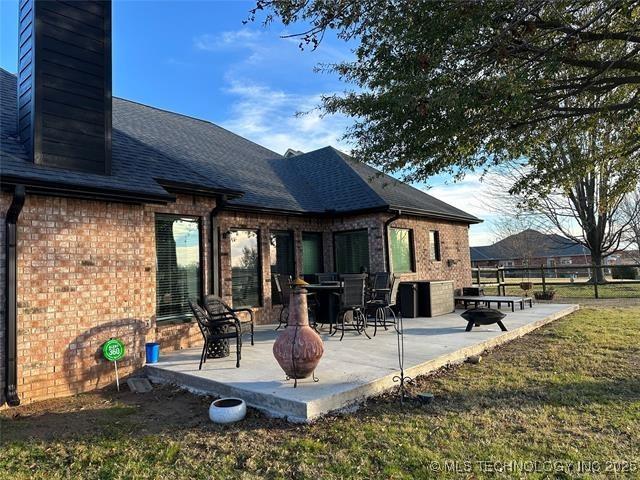 1821 W Lincoln St N, Broken Arrow, OK 74012 - back of property featuring a chimney, brick siding, a patio, and roof with shingles