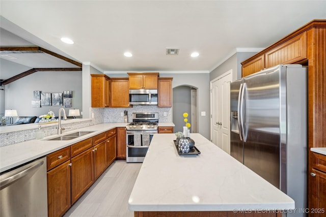 11710 S Willow St, Jenks, OK 74037 - kitchen featuring appliances with stainless steel finishes, arched walkways, a center island, backsplash, and crown molding