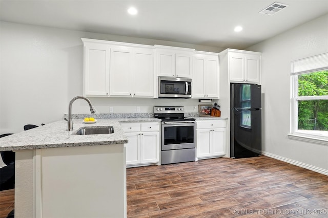 1325 Houston, Durant, OK 74701 - kitchen with appliances with stainless steel finishes, a peninsula, wood finished floors, white cabinets, and recessed lighting