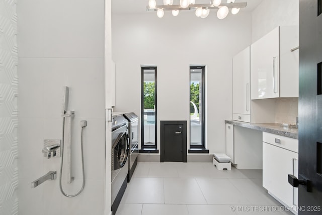 1226 W 109th Pl S, Jenks, OK 74037 - washroom featuring washing machine and clothes dryer, a towering ceiling, light tile patterned floors, and a chandelier
