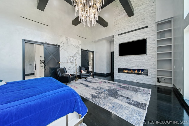 1226 W 109th Pl S, Jenks, OK 74037 - bedroom featuring a barn door, a high ceiling, a chandelier, wood finished floors, and a large fireplace