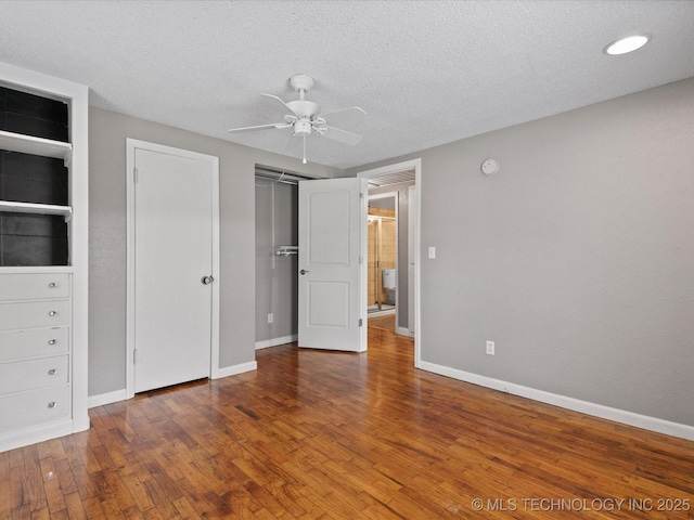 1322 Boundary Ave, Pawhuska, OK 74056 - unfurnished bedroom with wood finished floors, ceiling fan, a textured ceiling, and multiple closets