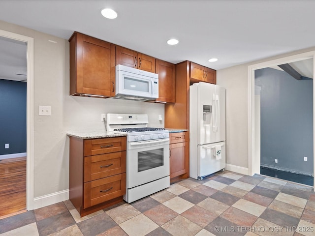 1322 Boundary Ave, Pawhuska, OK 74056 - kitchen with white appliances, brown cabinetry, stone finish floors, recessed lighting, and light stone counters