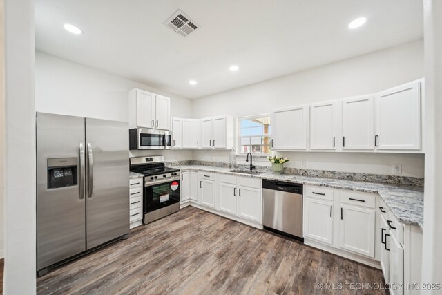 1102 W Main St, Beggs, OK 74421 - kitchen with stainless steel appliances, light stone counters, white cabinetry, wood finished floors, and recessed lighting