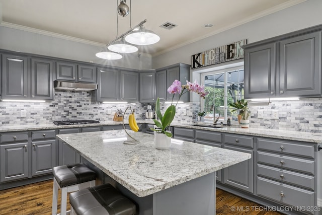 3701 W Dallas St, Broken Arrow, OK 74012 - kitchen with gray cabinets, ornamental molding, light stone countertops, stainless steel gas stovetop, and a kitchen island