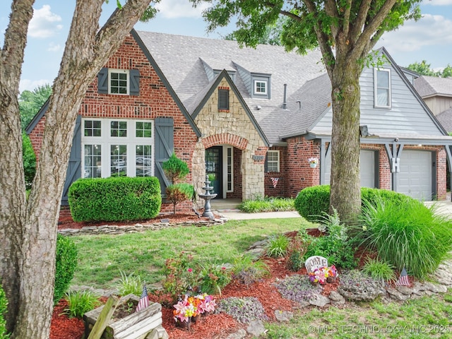 3701 W Dallas St, Broken Arrow, OK 74012 - tudor house featuring stone siding, brick siding, an attached garage, and roof with shingles