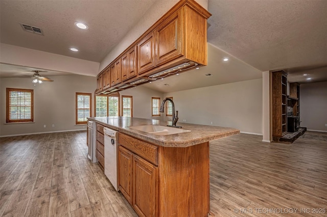 710 N Brethren Rd, Cushing, OK 74023 - kitchen featuring open floor plan, a textured ceiling, white dishwasher, brown cabinetry, and light wood-type flooring