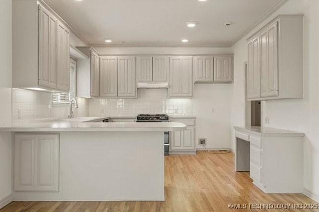 1620 S Florence Pl, Tulsa, OK 74104 - kitchen with a peninsula, under cabinet range hood, light countertops, recessed lighting, and crown molding
