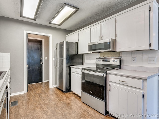 117 W Timberlane St, Broken Arrow, OK 74011 - kitchen featuring appliances with stainless steel finishes, light countertops, white cabinets, light wood finished floors, and backsplash