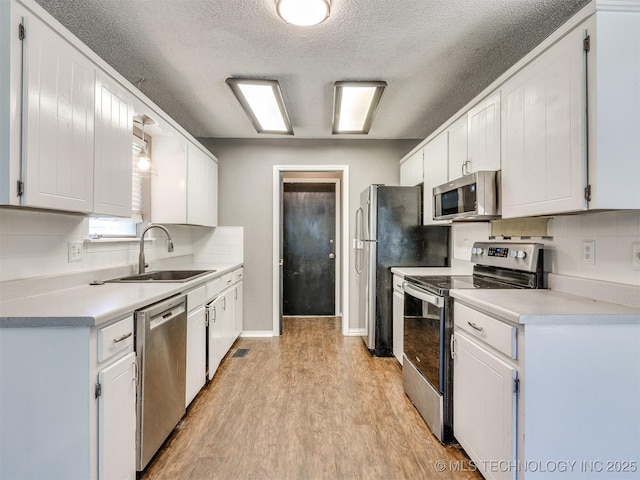 117 W Timberlane St, Broken Arrow, OK 74011 - kitchen featuring appliances with stainless steel finishes, light wood-style flooring, white cabinetry, a textured ceiling, and tasteful backsplash