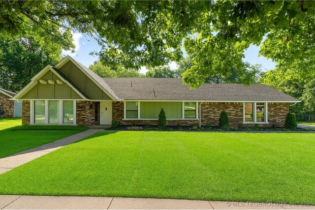 6905 S Redbud Ave, Broken Arrow, OK 74011 - view of front of property with board and batten siding, a front lawn, a shingled roof, and brick siding