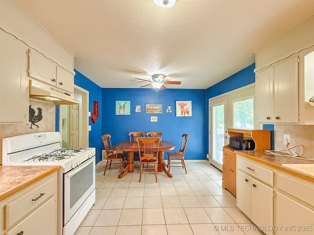 14174 County Road 3501, Ada, OK 74820 - kitchen featuring white range with gas cooktop, under cabinet range hood, a ceiling fan, a textured ceiling, and backsplash