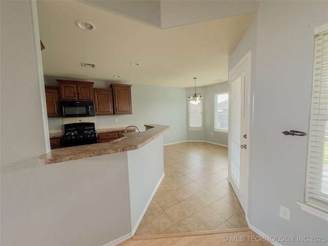 13155 E 132nd St N, Collinsville, OK 74021 - kitchen with black microwave, range, light tile patterned floors, a chandelier, and a peninsula