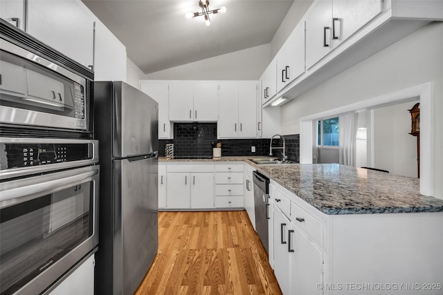 4620 S Winston Ave, Tulsa, OK 74135 - kitchen with appliances with stainless steel finishes, light wood finished floors, vaulted ceiling, decorative backsplash, and white cabinetry