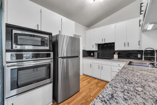 4620 S Winston Ave, Tulsa, OK 74135 - kitchen with stainless steel appliances, vaulted ceiling, light wood-style flooring, decorative backsplash, and white cabinetry