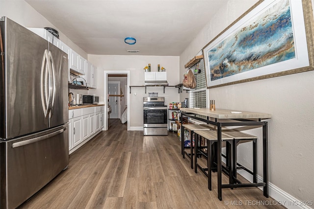 1208 NW 1st Ave, Ardmore, OK 73401 - kitchen with stainless steel appliances, white cabinetry, and dark wood finished floors