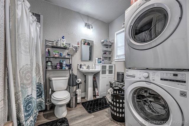 1208 NW 1st Ave, Ardmore, OK 73401 - full bath featuring stacked washer / drying machine, a textured wall, wood finished floors, a shower with curtain, and a textured ceiling