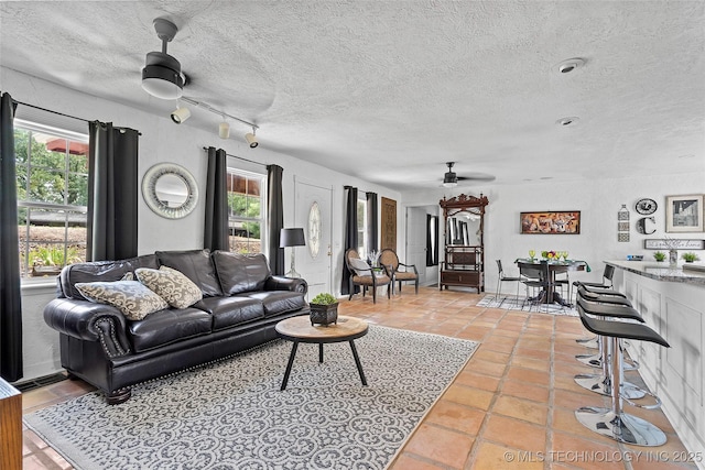 4080 Bud Dr, Sulphur, OK 73086 - living area featuring ceiling fan, plenty of natural light, light tile patterned floors, and a textured ceiling