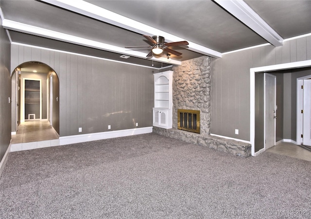 10046 E 29th St, Tulsa, OK 74129 - unfurnished living room with beam ceiling, ceiling fan, arched walkways, carpet, and a stone fireplace