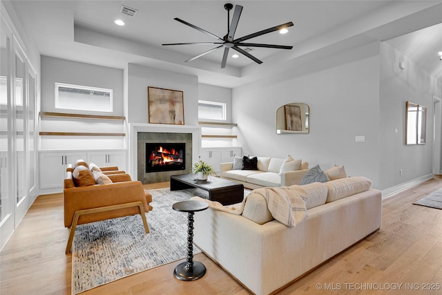 9613 E 119th Ct S, Bixby, OK 74008 - living room featuring a tray ceiling, light wood-style flooring, a ceiling fan, a fireplace, and recessed lighting