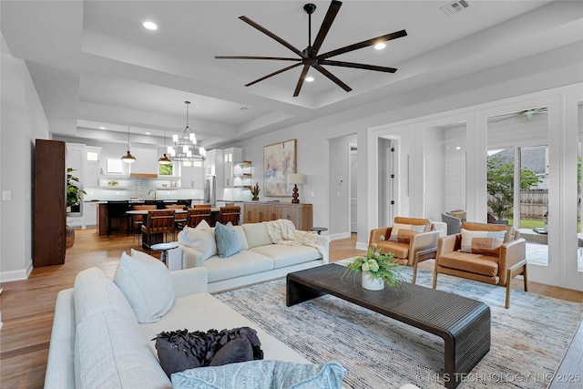 9613 E 119th Ct S, Bixby, OK 74008 - living room featuring a raised ceiling, a ceiling fan, light wood finished floors, a chandelier, and recessed lighting