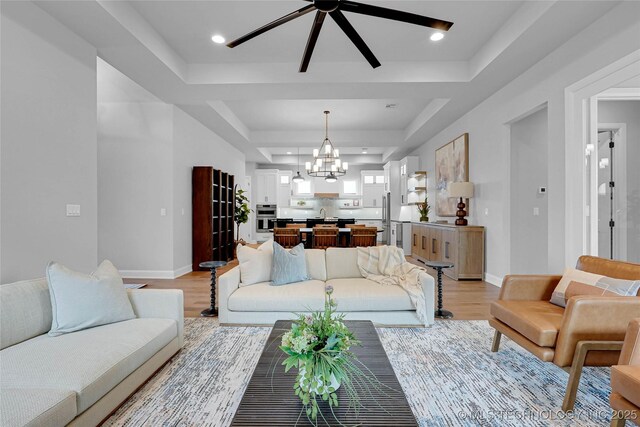 9613 E 119th Ct S, Bixby, OK 74008 - living area featuring a tray ceiling, a chandelier, light wood-type flooring, and a ceiling fan