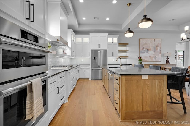 9613 E 119th Ct S, Bixby, OK 74008 - kitchen featuring appliances with stainless steel finishes, dark countertops, a raised ceiling, light wood-style flooring, and backsplash