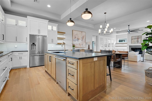 9613 E 119th Ct S, Bixby, OK 74008 - kitchen with appliances with stainless steel finishes, a tray ceiling, light wood finished floors, dark countertops, and recessed lighting