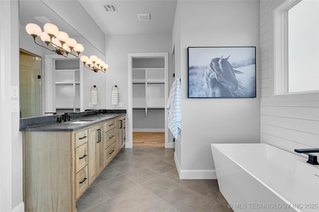 9613 E 119th Ct S, Bixby, OK 74008 - bathroom featuring double vanity, a freestanding tub, a walk in closet, a shower stall, and tile patterned floors