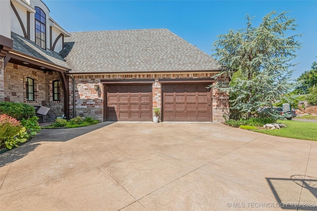1536 E 35th Pl, Tulsa, OK 74105 - view of side of home with a garage, concrete driveway, stone siding, and roof with shingles