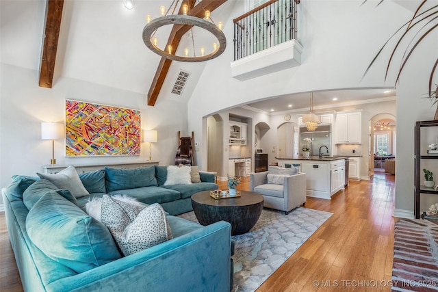1536 E 35th Pl, Tulsa, OK 74105 - living area featuring arched walkways, high vaulted ceiling, a chandelier, light wood-style floors, and crown molding