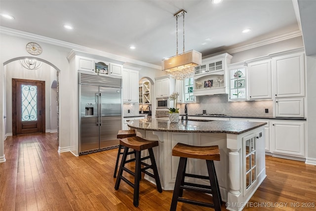 1536 E 35th Pl, Tulsa, OK 74105 - kitchen featuring built in appliances, arched walkways, open shelves, tasteful backsplash, and a center island with sink