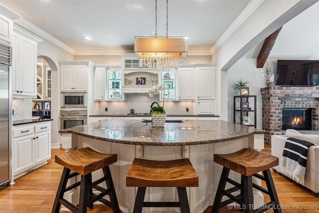 1536 E 35th Pl, Tulsa, OK 74105 - kitchen featuring built in appliances, white cabinets, decorative backsplash, a breakfast bar area, and ornamental molding