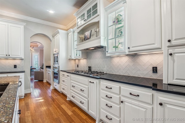 1536 E 35th Pl, Tulsa, OK 74105 - kitchen with stainless steel appliances, white cabinets, arched walkways, decorative backsplash, and light wood-style floors