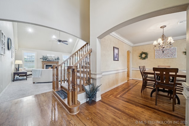 12225 S Glen Ct, Jenks, OK 74037 - dining space featuring arched walkways, a lit fireplace, ceiling fan, wood finished floors, and a chandelier