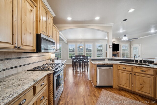 12225 S Glen Ct, Jenks, OK 74037 - kitchen featuring appliances with stainless steel finishes, arched walkways, wood finished floors, light stone counters, and decorative backsplash