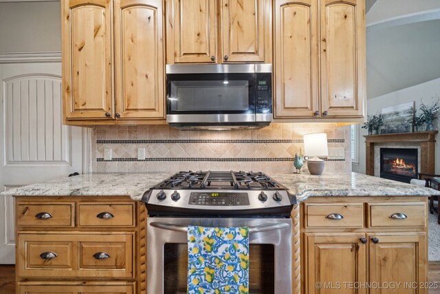 12225 S Glen Ct, Jenks, OK 74037 - kitchen featuring stainless steel appliances, decorative backsplash, a glass covered fireplace, and light stone countertops