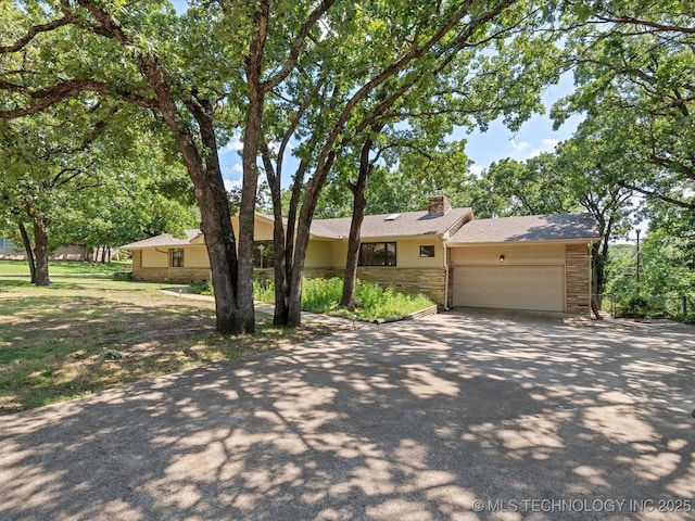 3321 Woodland Rd, Bartlesville, OK 74006 - single story home with stone siding, a chimney, concrete driveway, and a garage