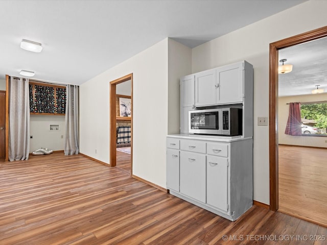 3321 Woodland Rd, Bartlesville, OK 74006 - kitchen featuring stainless steel microwave, light wood finished floors, light countertops, and white cabinetry