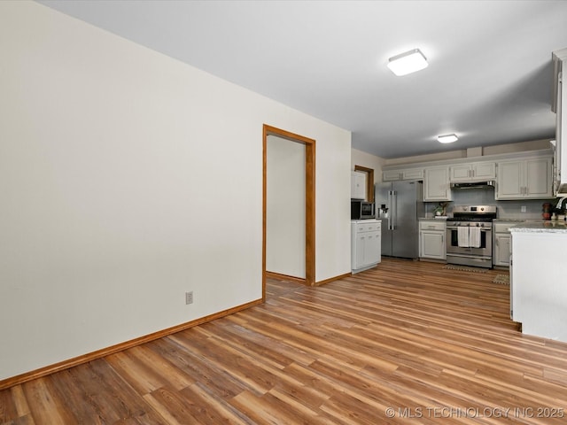 3321 Woodland Rd, Bartlesville, OK 74006 - kitchen with appliances with stainless steel finishes, light countertops, light wood-style flooring, under cabinet range hood, and decorative backsplash
