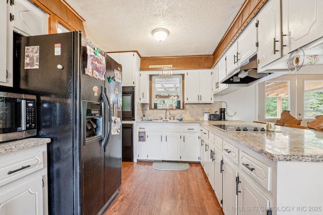 13201 W 86th St S, Sapulpa, OK 74066 - kitchen featuring black appliances, a textured ceiling, under cabinet range hood, white cabinets, and light wood-style floors