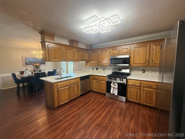 4001 Chaucer, Muskogee, OK 74403 - kitchen featuring appliances with stainless steel finishes, brown cabinetry, light countertops, dark wood-style flooring, and a textured ceiling