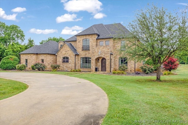 3892 Folsom Rd, Durant, OK 74701 - french provincial home featuring a front yard, curved driveway, brick siding, and roof with shingles